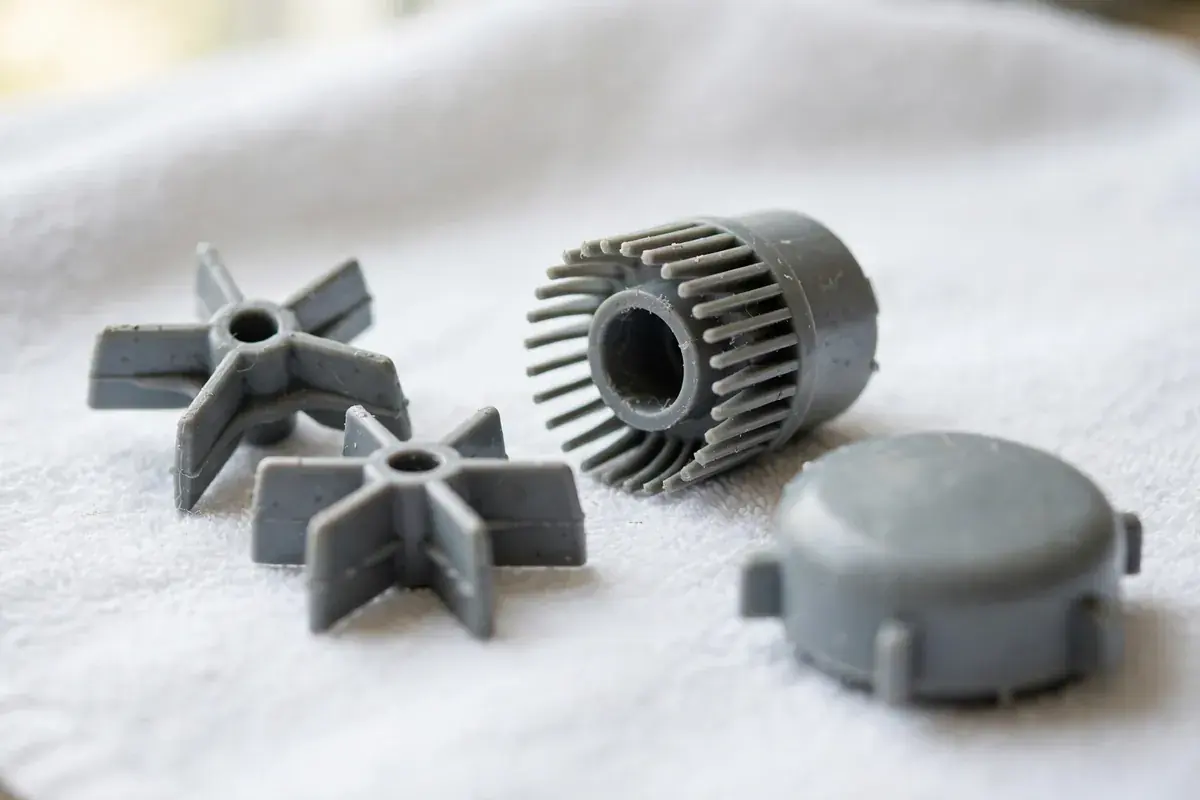 Two small gray plastic agitator dogs and a coupling on a white towel